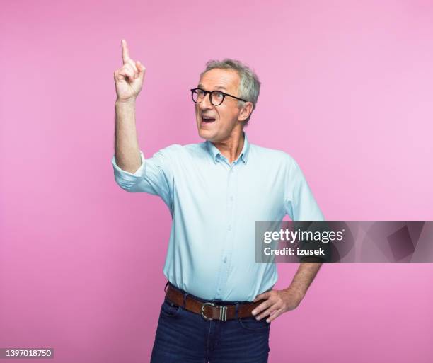 excited senior man gesturing while looking up - arm pointing stock pictures, royalty-free photos & images