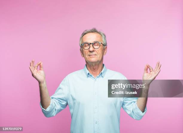 entspannter älterer mann, der mit geschlossenen augen meditiert - aged man portrait studio stock-fotos und bilder