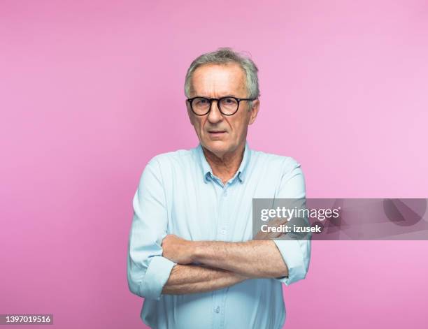 serious retired senior man with arms crossed - alleen één seniore man stockfoto's en -beelden