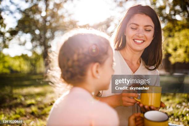 glückliche alleinerziehende mutter im gespräch mit ihrer kleinen tochter in der natur. - tea outdoor stock-fotos und bilder