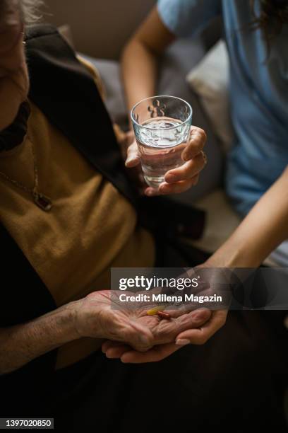 nahaufnahme einer krankenschwester, die ihrer älteren patientin mit ihren pillen hilft - heranlocken stock-fotos und bilder