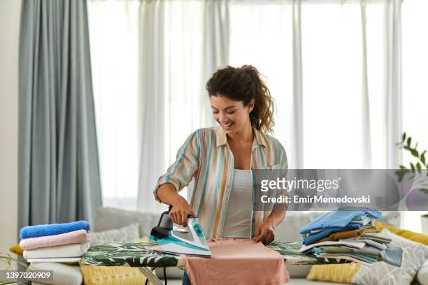 hermosa mujer planchando algo de ropa en casa - iron fotografías e imágenes de stock