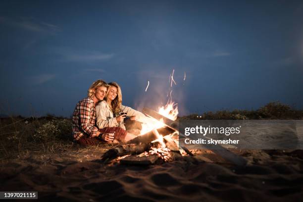 happy relaxed couple enjoying in their date night by the campfire. - bonfire stock pictures, royalty-free photos & images