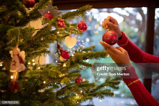 uk, richmond, london, close-up of woman's hands holding christmas ornament at christmas tree - decorare l'albero di natale foto e immagini stock