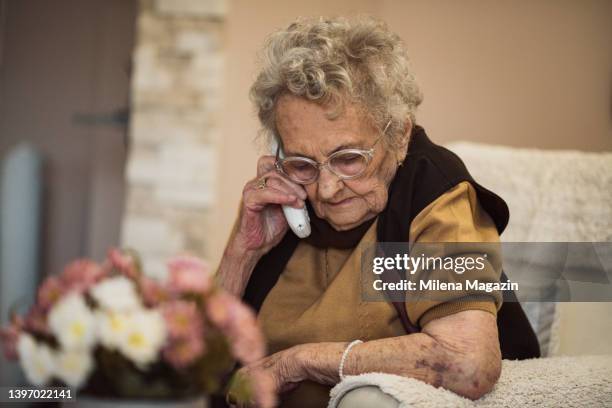 señora de 90 años hablando en un teléfono fijo - teléfono con cable fotografías e imágenes de stock