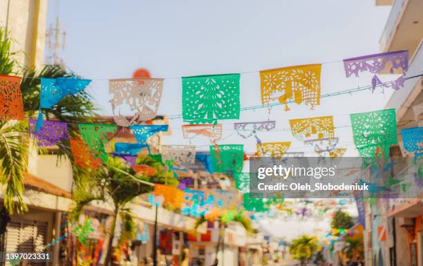 flaggen wehen auf der straße einer kleinen mexikanischen stadt - mexico stock-fotos und bilder