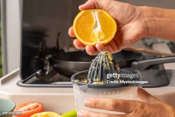 young woman in her camper van making a fresh squeezed orange juice staring the day with healthy food, van life concept - woman squeezing orange stockfoto's en -beelden