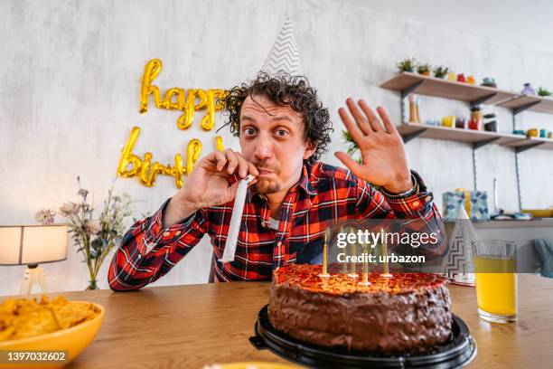 junger mann, der mit seinem freund in einem videoanruf spricht, während er seinen geburtstag feiert - blowing out candles pov stock-fotos und bilder