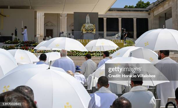 Priests face the figure of Our Lady of Fatima as they protect themselves against the strong sun with white umbrellas at the end of the farewell...