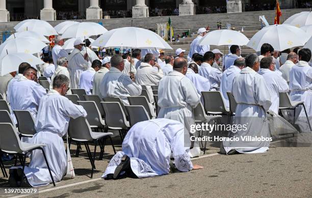 Priests protect themselves against the strong sun with white umbrellas as they kneel and pray at the end of the farewell procession during the last...