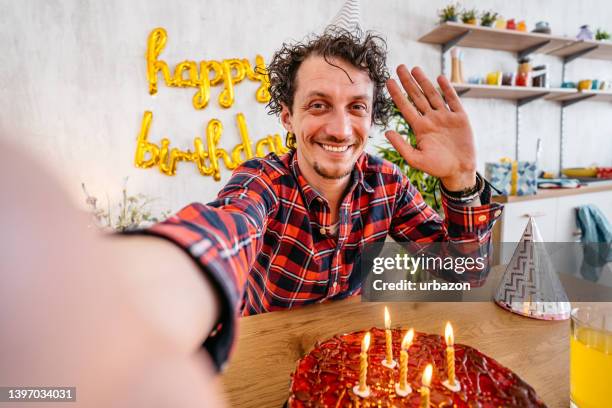 junger mann, der mit seinem freund in einem videoanruf spricht, während er seinen geburtstag feiert - blowing out candles pov stock-fotos und bilder