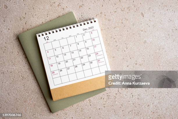 december 2022 desk calendar and green note pad on concrete background, top view. copy space. - monday friday stock pictures, royalty-free photos & images