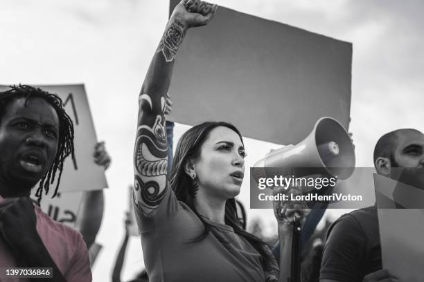 young woman shouting on megaphone during a protest - angry protestor stock pictures, royalty-free photos & images