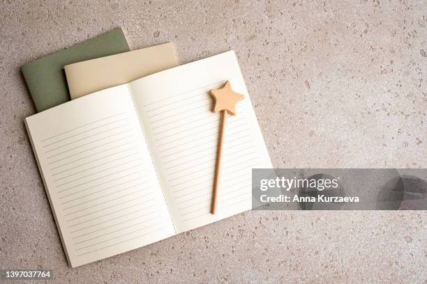 three note pads stacked - two closed and one with blank lined paper open and a wooden wand like a magic wand, top view. with copy space. - 手品師の杖 ストックフォトと画像