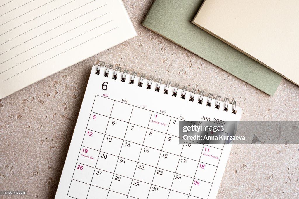 Office desk and stationery with laptop, note pads, June 2022 desk calendar on concrete background, top view. Copy space.