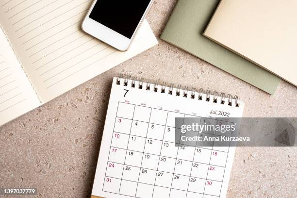 office desk and stationery with laptop, note pads, smart phone, july 2022 desk calendar on concrete background, top view. copy space. - juli bildbanksfoton och bilder