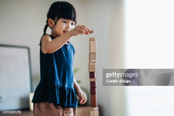 creative little asian girl having fun playing wooden building blocks at home. learning through play concept - wood block stacking stock pictures, royalty-free photos & images