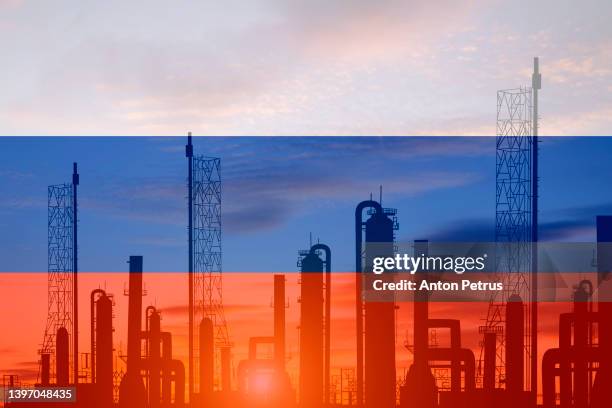 oil refinery plant of petroleum on the background of of the russian flag - punishment stocks stock pictures, royalty-free photos & images