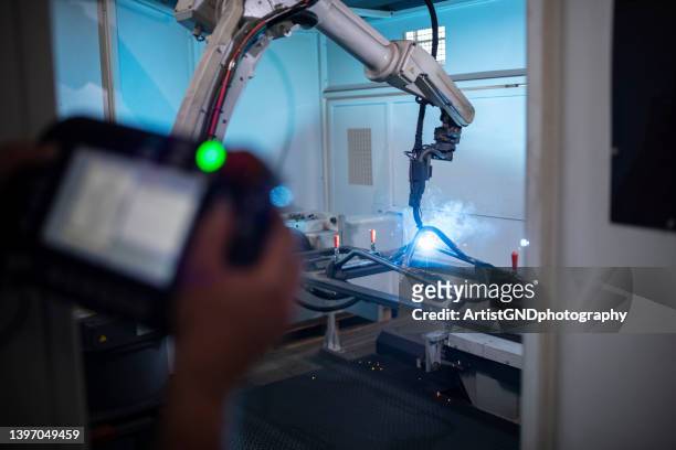 worker using remote to control professional welding robot. - op afstand bediend stockfoto's en -beelden
