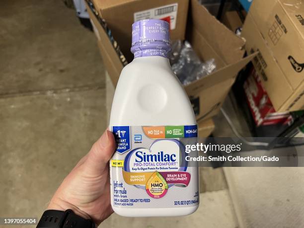 Person's hand holding Similac baby formula from Abbott Laboratories above shipment boxes in Lafayette, California, May 13, 2022. Shortages of baby...