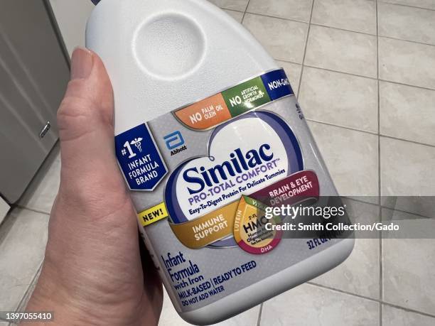 Person's hand holding a bottle of Similac baby formula from Abbott Laboratories in Lafayette, California, May 13, 2022. Shortages of baby formula...