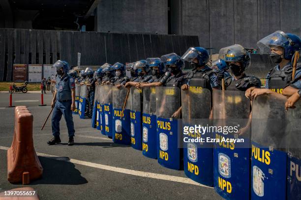 Riot police stand guard as Filipinos take part in a protest against election results outside the Philippine International Convention Center, where...