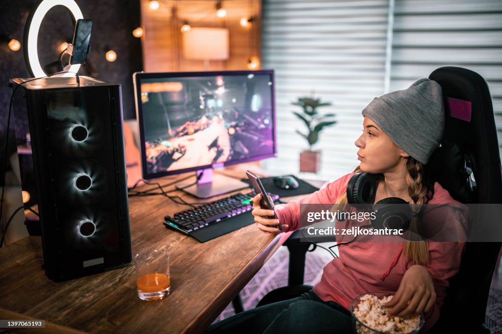 Gaming girl eating popcorn and looks at her phone