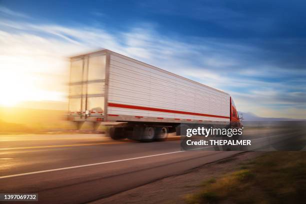 red and white 16 wheeler with cargo speeding at sunrise on a single lane road usa - articulated lorry stock pictures, royalty-free photos & images