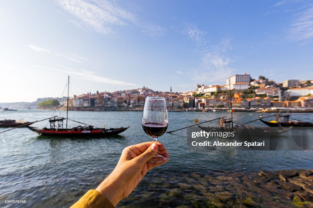 Drinking port wine from a glass with view towards Porto skyline, personal perspective view, Porto, Portugal