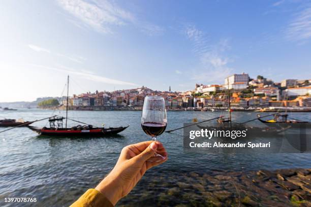 drinking port wine from a glass with view towards porto skyline, personal perspective view, porto, portugal - oporto fotografías e imágenes de stock