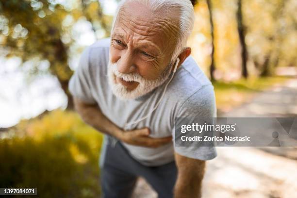 senior man athlete having heart problems during exercise - attack sporting position stockfoto's en -beelden