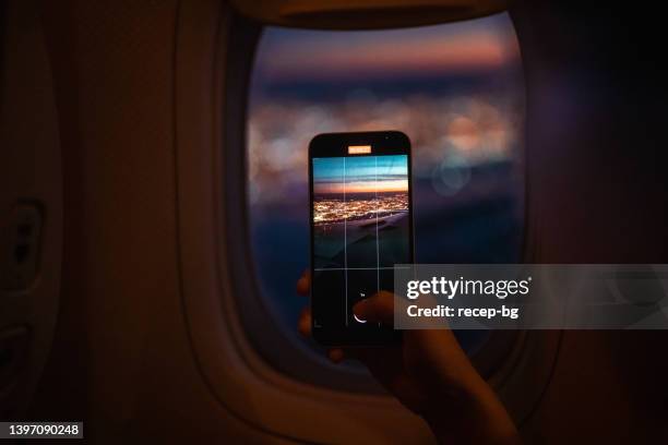 passenger taking photos of scenery through airplane window with smart phone - airplane phone stock pictures, royalty-free photos & images