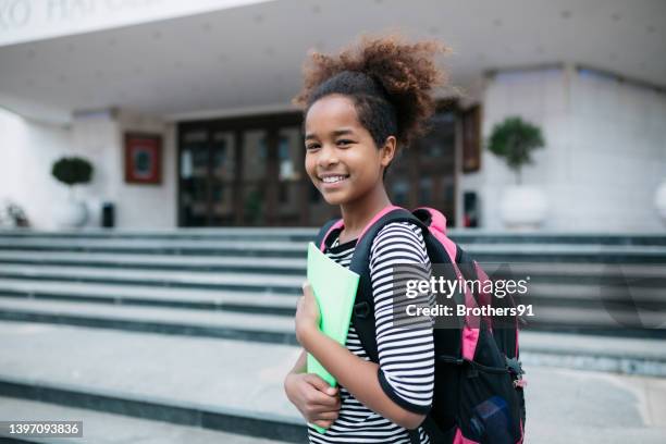 happy little girl standing in front of the school building - 10 11 jaar stockfoto's en -beelden