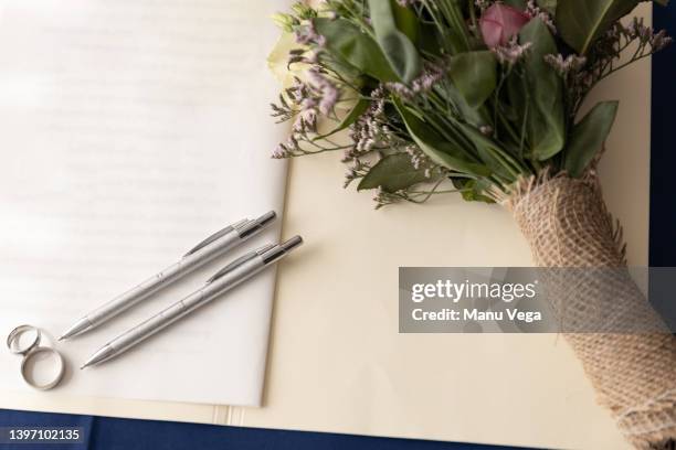 marriage certificate, silver wedding rings and pens on the table. they symbolize the beginning of a lifelong union of love. - alliance mariage stock-fotos und bilder