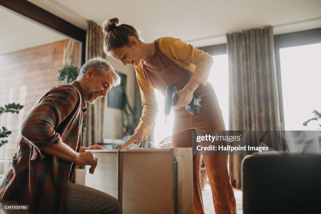 Father and teen daughter assembling new furniture in the renovated apartment
