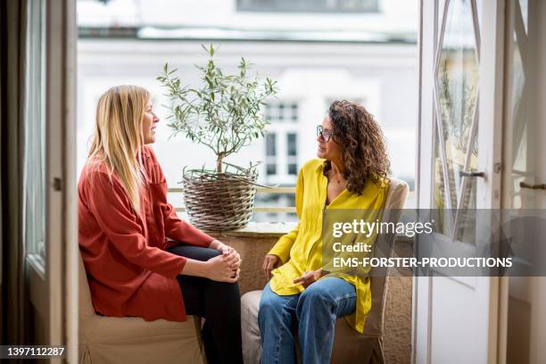 two beautiful woman talking together on cozy balcony - two houses side by side stock pictures, royalty-free photos & images