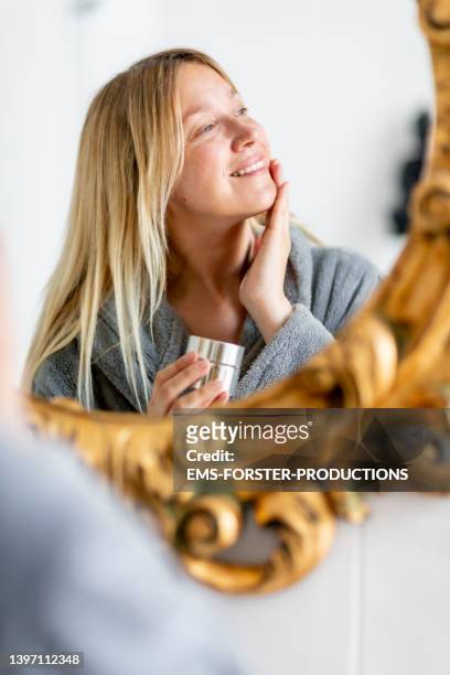 portrait of woman looking at her mirror image in the morning - mature woman face beauty stock-fotos und bilder