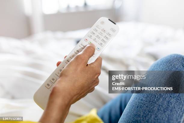 woman is using a remote control in her bed room - 50 watching video stock pictures, royalty-free photos & images