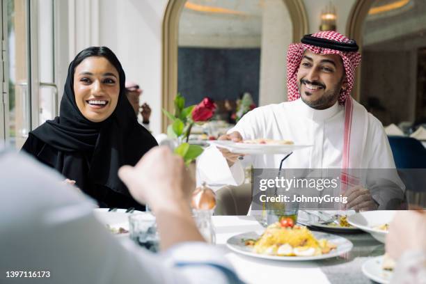young saudi friends enjoying lunch together at restaurant - logement social stockfoto's en -beelden
