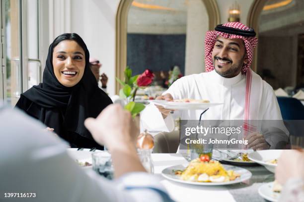 young saudi friends enjoying lunch together at restaurant - saudi relaxing stock pictures, royalty-free photos & images