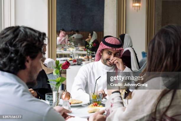 candid sideways glance between saudi friends at lunch - saudi lunch stock pictures, royalty-free photos & images