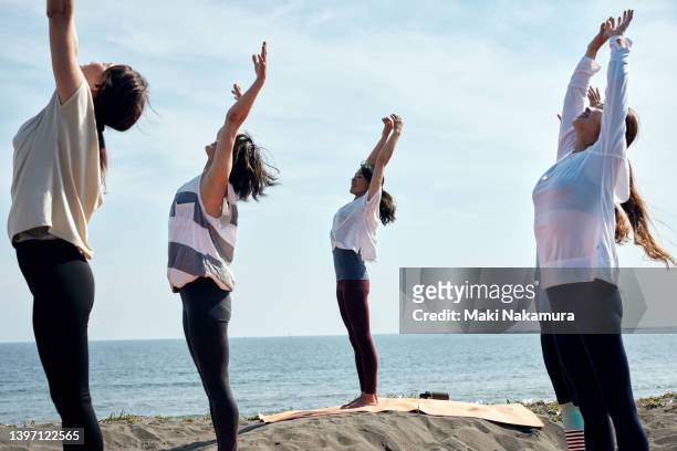 women enjoying yoga on the beach. - friendly match stockfoto's en -beelden
