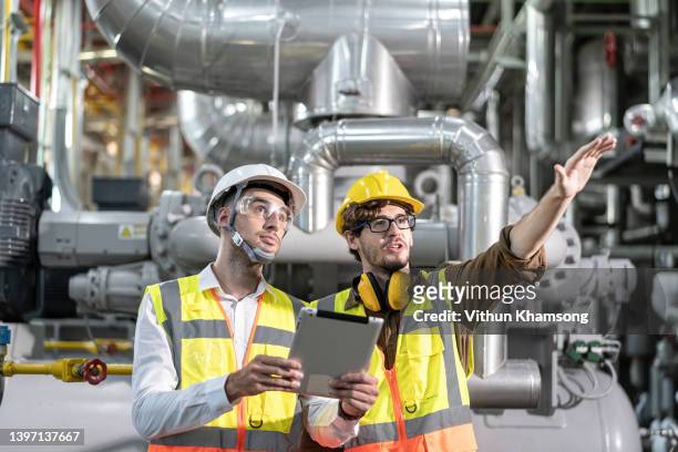 industry engineer team worker teaching help friend operate control heavy machine in factory, two engineer working at industrial pipeline zone - sewage services stock pictures, royalty-free photos & images