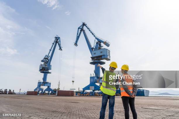 trabalhadores portuários homens e mulheres trocam de trabalho em frente a guindastes portuários - longshoremen - fotografias e filmes do acervo