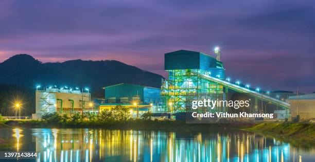 power plant and pipeline biomass type, biomass power plant include fuel,boiler,steam turbine, cooling tower, and stack, water reflection and sky - biomass renewable energy source stockfoto's en -beelden