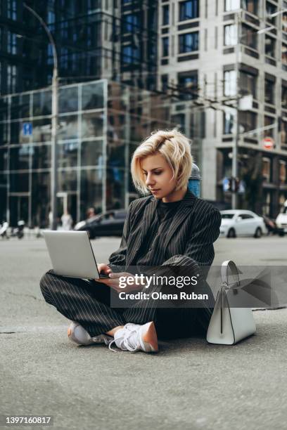 young woman working on laptop sitting on asphalt. - smart shoes stock pictures, royalty-free photos & images