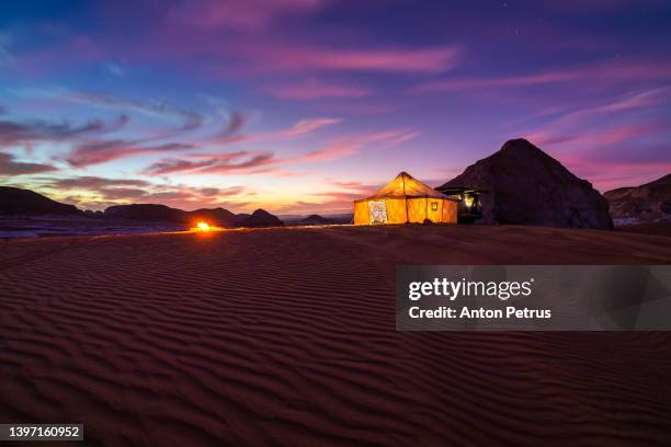 camp in the white desert at sunset with a bonfire under the starry sky.  egypt, sahara desert - zelt nacht stock-fotos und bilder