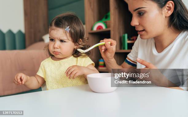 mutter füttert ihr mädchen - refusing stock-fotos und bilder