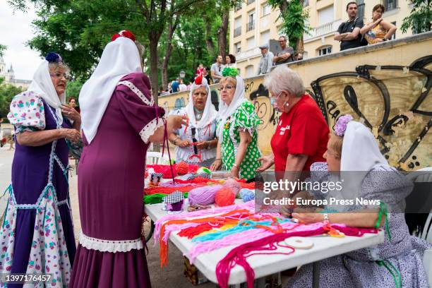 Several women dressed as chulapas, at a wool stall, at an event of the Federacion Grupos Tradicionales madrileños during the San Isidro festivities,...