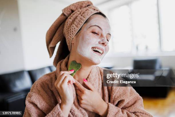 happy woman at home  does a face massage with a gouache scraper - spooning stock pictures, royalty-free photos & images